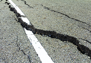 Large crack and raised pavement in road
